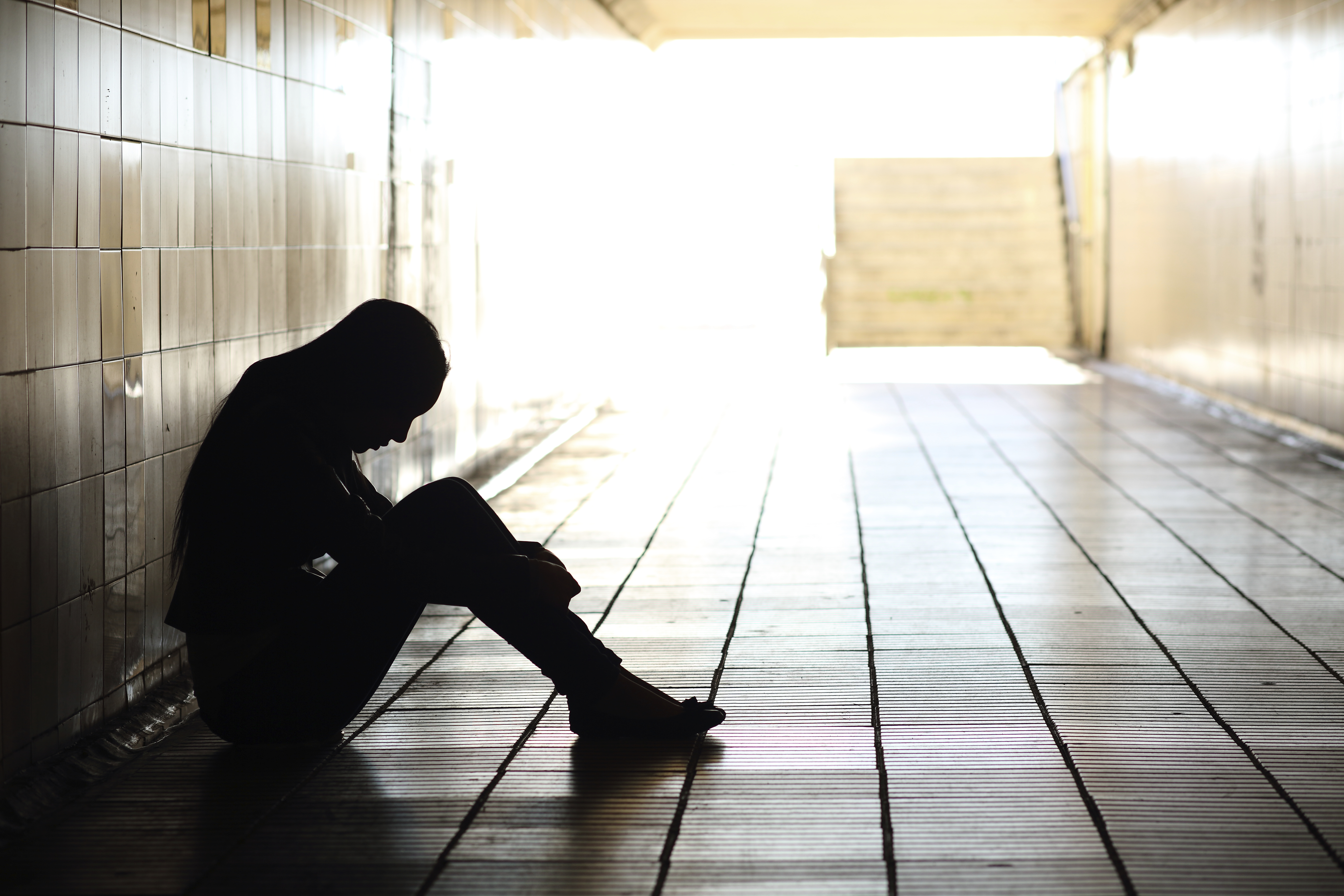 Teenager depressed sitting under a walkway